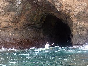 MacLaren on his surfboard, sitting in the mouth of the sea cave at Chicken Hill, Galapagos Islands.